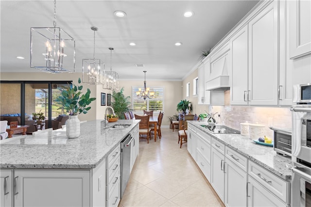 kitchen with stainless steel appliances, white cabinets, sink, and a kitchen island with sink