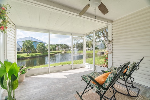 sunroom with ceiling fan and a water view