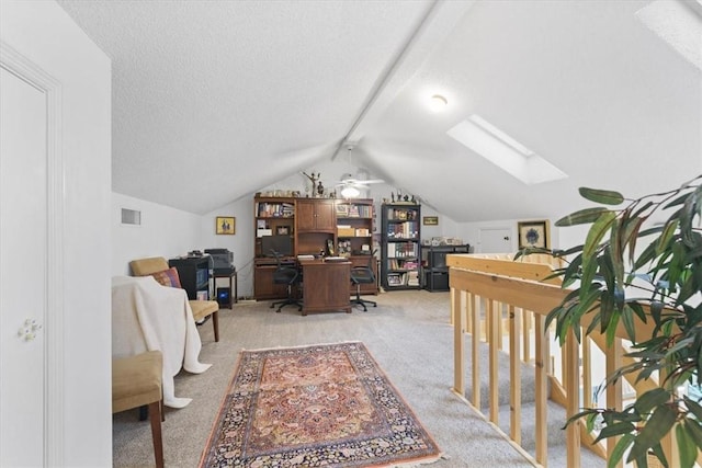 carpeted home office with a textured ceiling, lofted ceiling with skylight, and ceiling fan