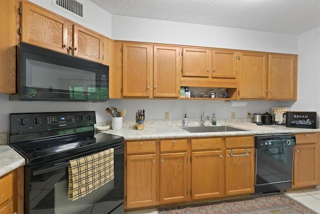 kitchen with a textured ceiling, sink, light tile patterned floors, and black appliances