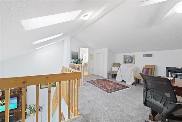 carpeted office with visible vents and vaulted ceiling with skylight