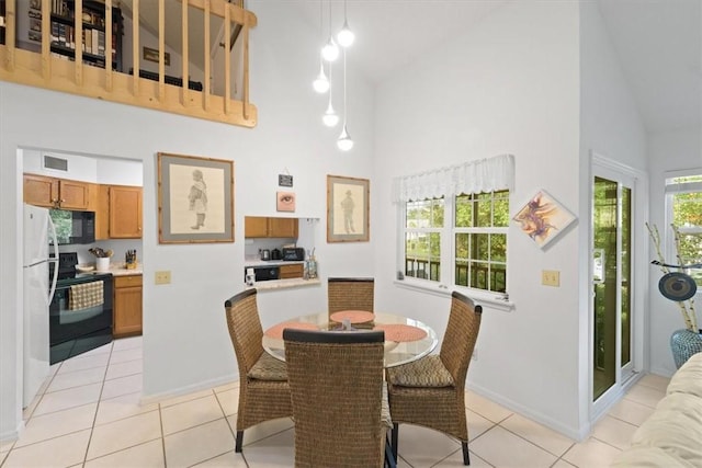 dining space featuring light tile patterned floors, baseboards, visible vents, and high vaulted ceiling