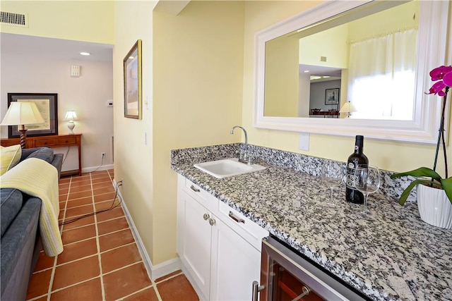 kitchen featuring baseboards, visible vents, light stone counters, tile patterned flooring, and a sink