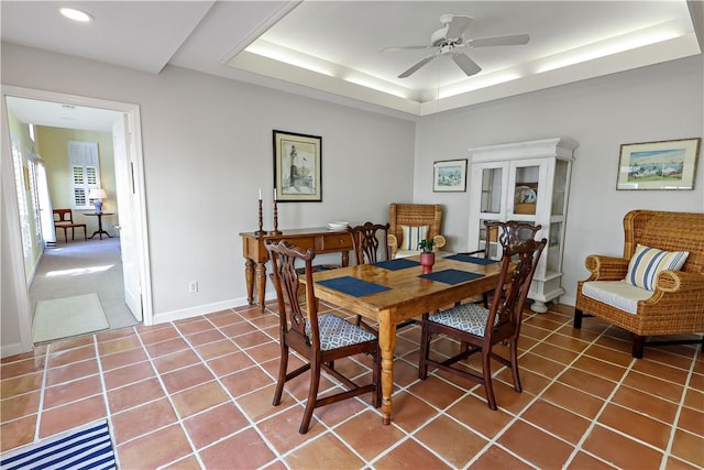 dining room with ceiling fan, recessed lighting, baseboards, tile patterned floors, and a tray ceiling