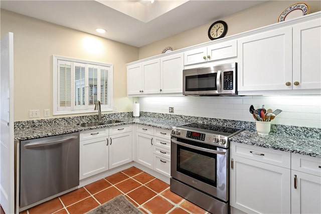 kitchen featuring stainless steel appliances, tasteful backsplash, white cabinets, a sink, and dark tile patterned flooring