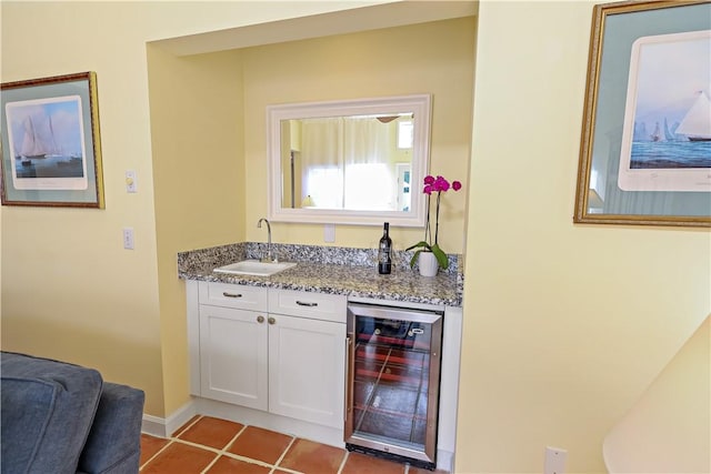 bar featuring light tile patterned floors, wine cooler, a sink, and baseboards