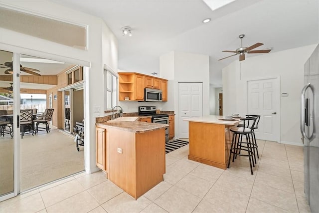 kitchen featuring appliances with stainless steel finishes, sink, kitchen peninsula, a breakfast bar, and light tile patterned floors