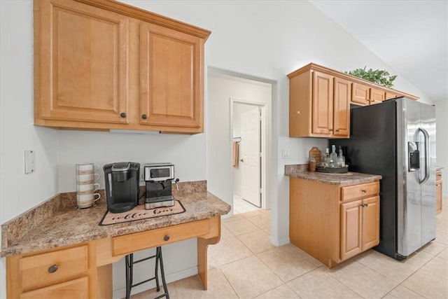 kitchen featuring stainless steel fridge with ice dispenser, light tile patterned floors, light stone countertops, vaulted ceiling, and a breakfast bar