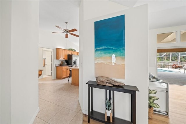 kitchen featuring stainless steel refrigerator with ice dispenser, ceiling fan, light tile patterned floors, and high vaulted ceiling