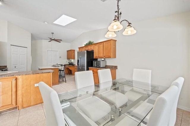 tiled dining area with ceiling fan and lofted ceiling with skylight