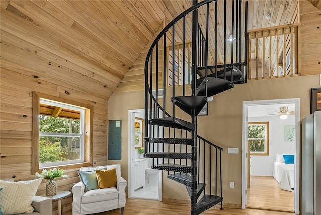 staircase featuring vaulted ceiling, wood ceiling, electric panel, and wood finished floors