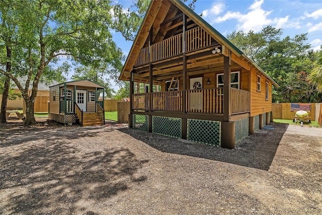 rear view of house with fence, an outbuilding, and driveway