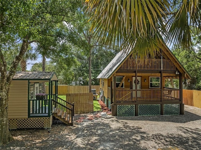 view of front facade with fence, an outbuilding, a porch, and metal roof
