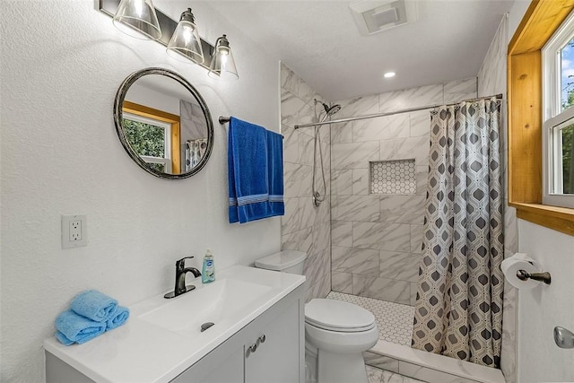 bathroom featuring vanity, toilet, tiled shower, and marble finish floor