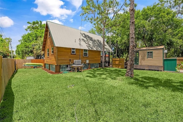 back of house featuring a lawn, a fenced backyard, central AC, and an outdoor structure