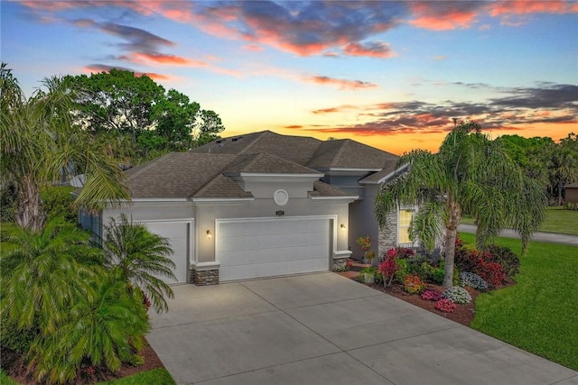 mediterranean / spanish house featuring roof with shingles, stucco siding, concrete driveway, a garage, and stone siding