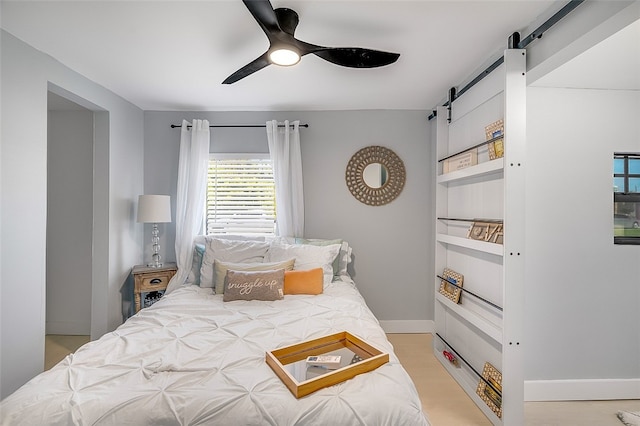 bedroom with ceiling fan and a barn door