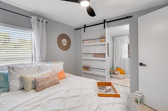 bedroom featuring a barn door and ceiling fan