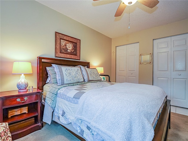 bedroom with a textured ceiling, ceiling fan, light carpet, and multiple closets