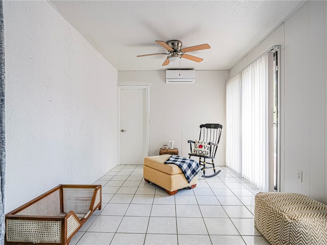 living area with a wall mounted air conditioner, wood walls, ceiling fan, light tile patterned floors, and a textured ceiling