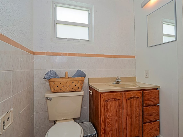 bathroom featuring vanity, tile walls, and toilet