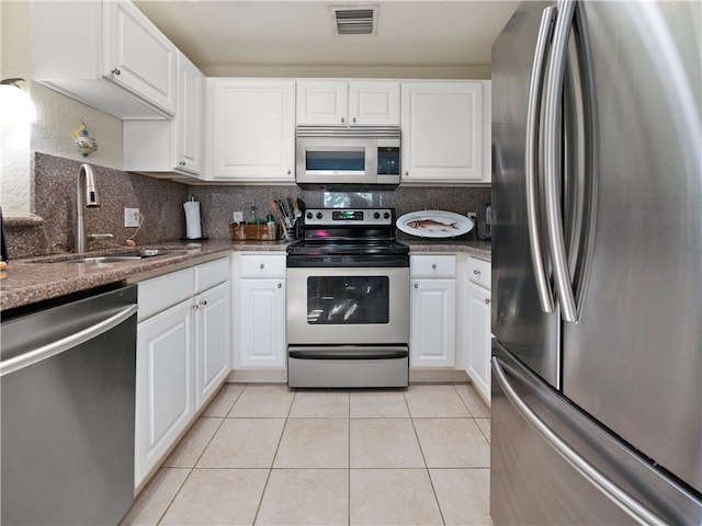 kitchen with stainless steel appliances, white cabinets, sink, light tile patterned floors, and backsplash