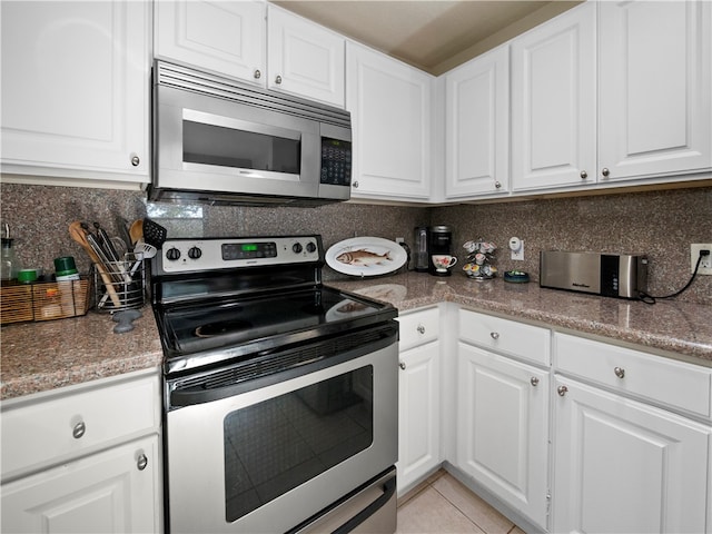 kitchen featuring appliances with stainless steel finishes, decorative backsplash, light tile patterned floors, and white cabinets