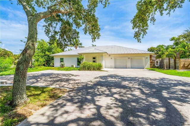 649 E Causeway Blvd, Vero Beach, FL 32963 - ranch-style house with concrete driveway, stucco siding, a garage, and a metal roof