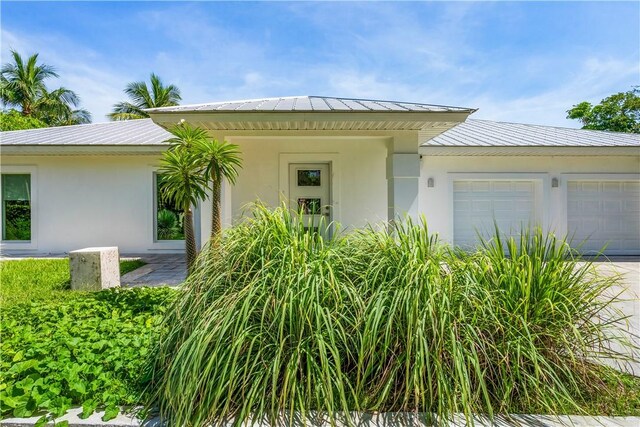 649 E Causeway Blvd, Vero Beach, FL 32963 - view of front of home with a garage, driveway, stucco siding, and a metal roof