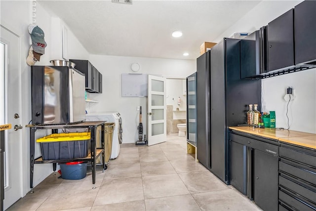 649 E Causeway Blvd, Vero Beach, FL 32963 - kitchen with washer and clothes dryer, light tile patterned floors, recessed lighting, light countertops, and dark cabinetry