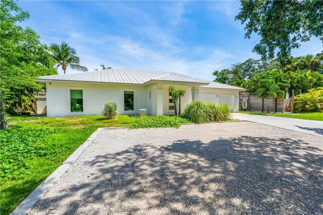 649 E Causeway Blvd, Vero Beach, FL 32963 - view of front of property with stucco siding, driveway, a garage, a metal roof, and a standing seam roof