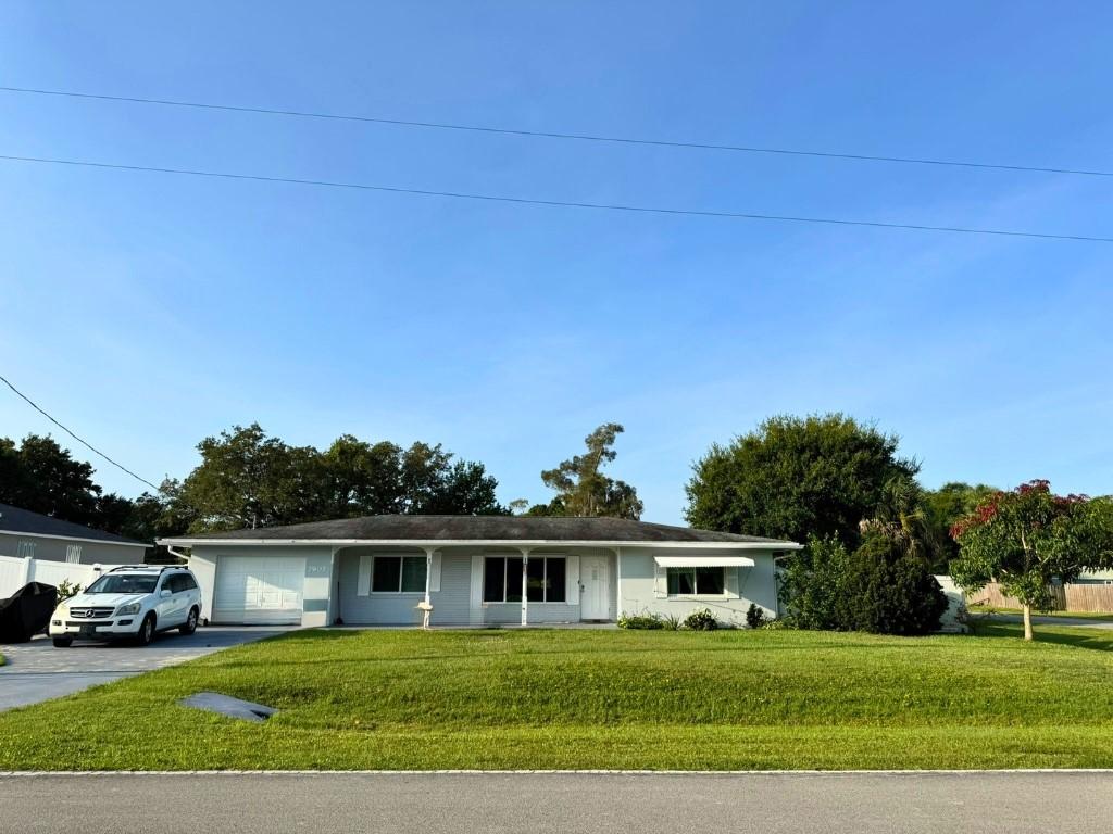 7907 Sebastian Rd, Fort Pierce, FL 34951 - ranch-style home with concrete driveway, an attached garage, and a front lawn