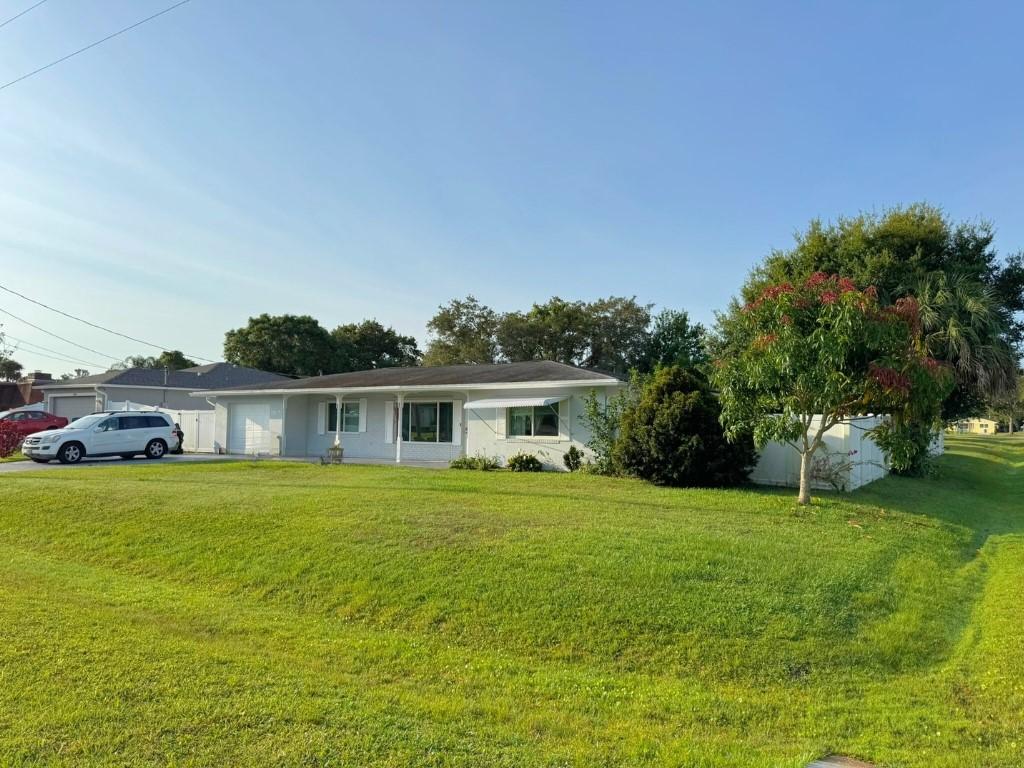 7907 Sebastian Rd, Fort Pierce, FL 34951 - ranch-style house with an attached garage, a front yard, and asphalt driveway