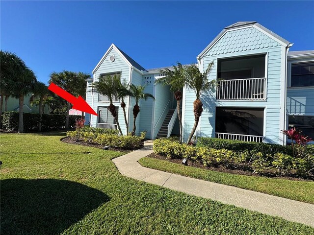 view of front of property with a balcony and a front lawn