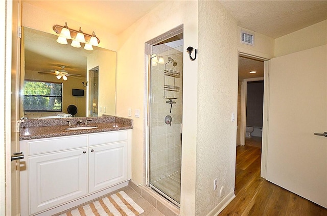 bathroom with vanity, hardwood / wood-style flooring, a shower with shower door, and ceiling fan