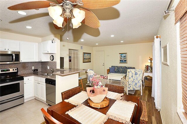 kitchen featuring kitchen peninsula, white cabinetry, ceiling fan, and appliances with stainless steel finishes