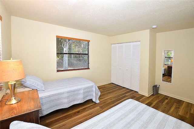 bedroom featuring a textured ceiling, dark hardwood / wood-style flooring, and a closet