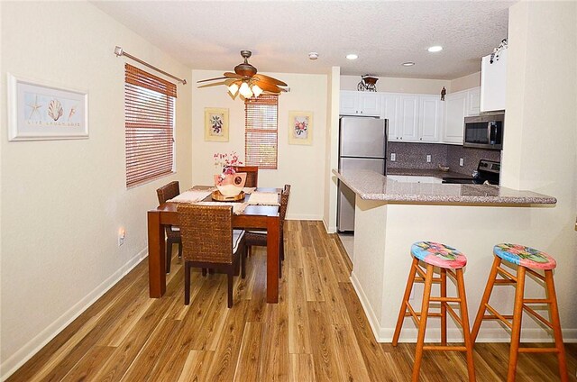 kitchen with ceiling fan, appliances with stainless steel finishes, white cabinetry, tasteful backsplash, and kitchen peninsula