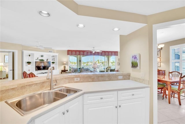 kitchen with white cabinets, ceiling fan with notable chandelier, light tile patterned floors, and sink