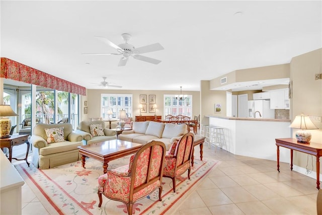 tiled living room featuring ceiling fan with notable chandelier