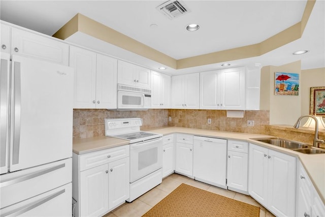 kitchen featuring white appliances, tasteful backsplash, light tile patterned floors, sink, and white cabinets