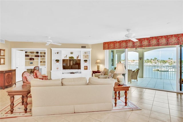 living room featuring built in features, light tile patterned floors, and ceiling fan