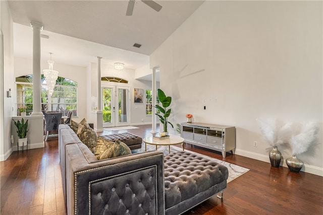 living room featuring ceiling fan with notable chandelier, dark wood-type flooring, and decorative columns