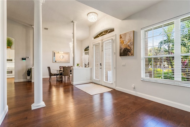 foyer with a notable chandelier, dark hardwood / wood-style floors, french doors, and decorative columns