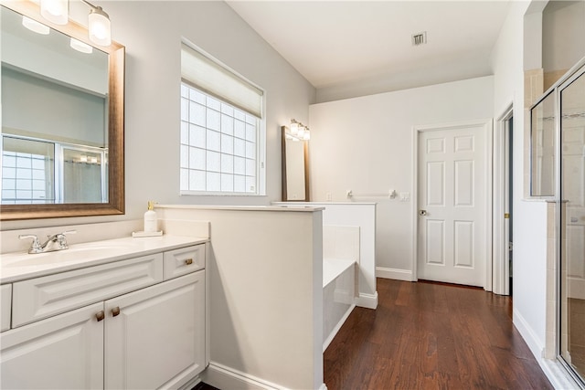 bathroom with plus walk in shower, hardwood / wood-style floors, and vanity