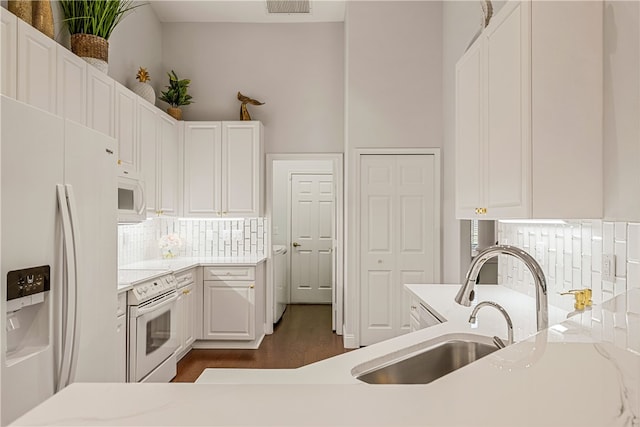 kitchen with tasteful backsplash, white appliances, sink, white cabinets, and dark hardwood / wood-style floors