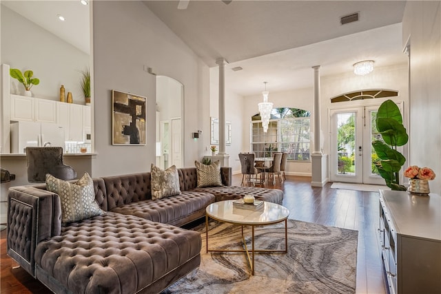 living room featuring ornate columns, dark hardwood / wood-style flooring, and high vaulted ceiling