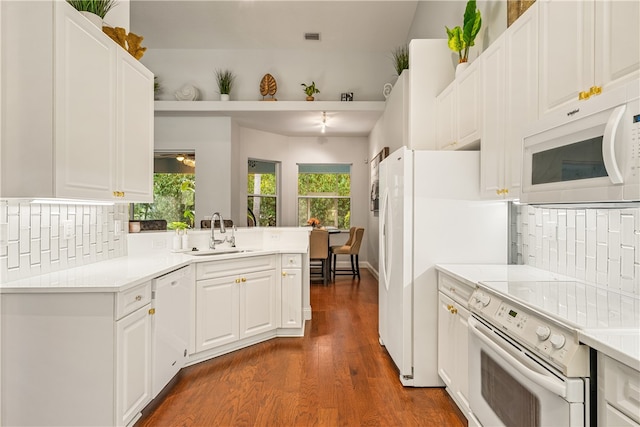 kitchen with sink, dark hardwood / wood-style flooring, kitchen peninsula, white appliances, and white cabinets