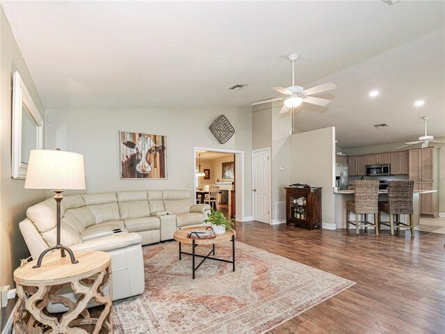 living room with light hardwood / wood-style floors, vaulted ceiling, and ceiling fan