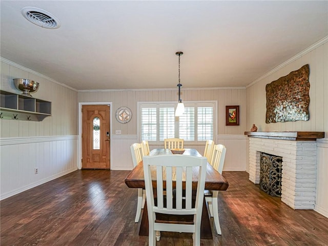 dining room with a brick fireplace, dark wood-type flooring, and crown molding